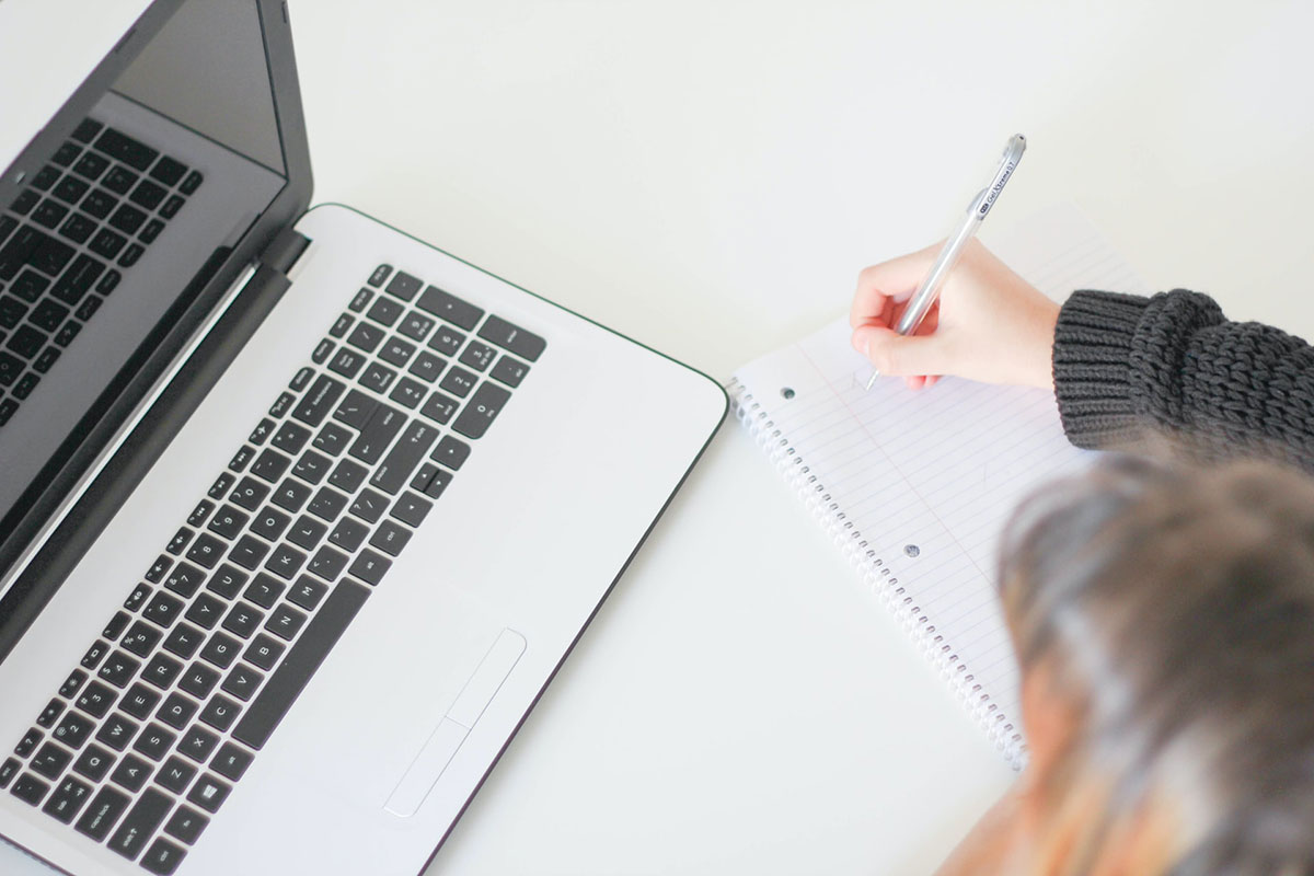 A picture of a woman writing on notebook. A photo by J.Kelly Briton on Unsplash
