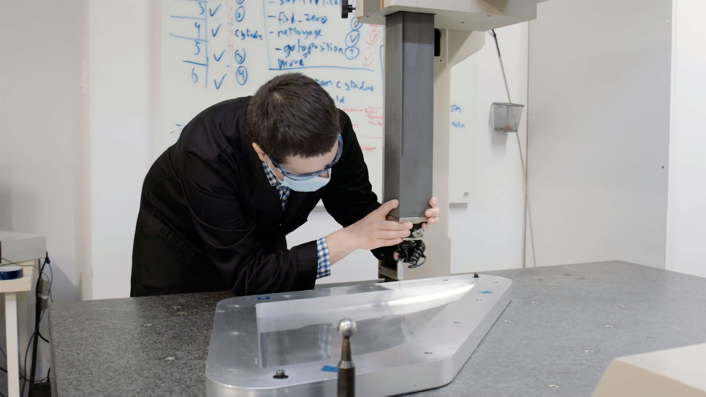 A picture of a young man in a black lab coat operating a machine
