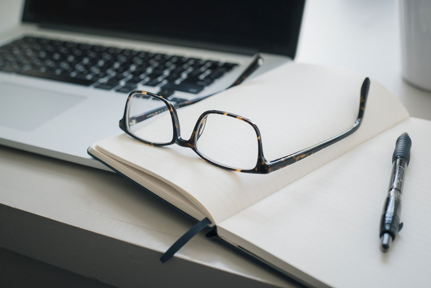 A photo of black framed eyeglasses and black pn by Trent Erwin on Unsplash